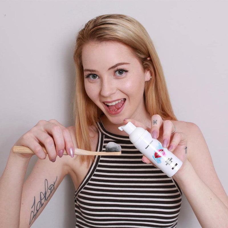 Kvinna med Diamond Smile tandblekningsskum och en tandborste i handen