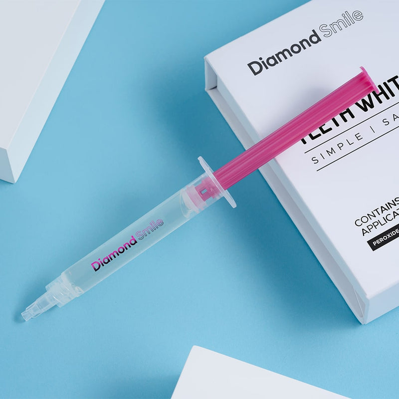 En tandblekningsgel i en spruta för att bleka tänderna hemma med en blå bakgrund