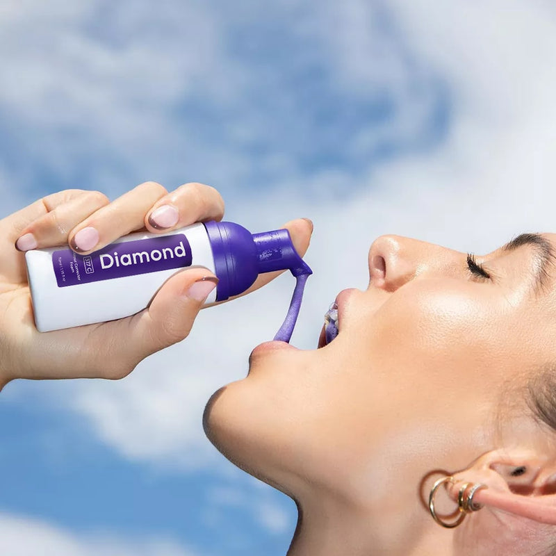 Kvinna med Diamond Smile lila tandblekningsskum för färgkorrigering i handen